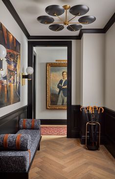 a hallway with two couches and paintings on the wall above them, along with wooden flooring