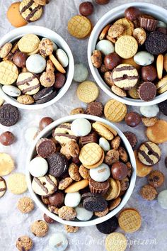 two white bowls filled with cookies and other snacks