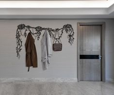 a coat rack with three coats hanging from it's hooks and two purses on the wall