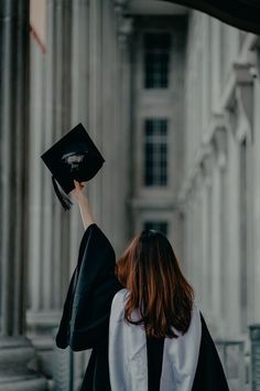 a woman in graduation gown throwing her cap into the air