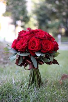 a bouquet of red roses sitting in the grass