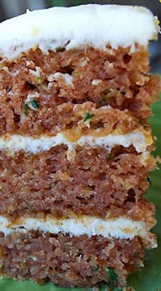 a piece of cake sitting on top of a green leafy plate with white frosting