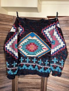 This gorgeous hand knit aztec wool sweater was lovingly created by Georgene Johnson of Hays Kansas.  The sweater measures 40 inches wide by 30 inches long. It has a sleeve length of 23 inches. Care: Dry clean or hand wash cold/gentle cycle. Condition: Very Good Bohemian Jacquard Knit Sweater, Multicolor Long Sleeve Sweater With Geometric Pattern, Multicolor Geometric Pattern Long Sleeve Sweater, Bohemian Long Sleeve Jacquard Knit Sweater, Bohemian Knit Sweater With Fair Isle Pattern, Nordic Multicolor Sweater For Fall, Multicolor Nordic Sweater For Fall, Bohemian Knitted Patterns For Winter, Bohemian Jacquard Knit Winter Sweater