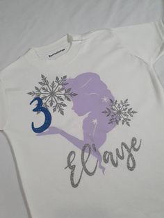 a t - shirt with the number three on it and a silhouette of a woman holding snowflakes