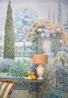 a table with fruit on it in front of a wallpapered background that has trees and bushes