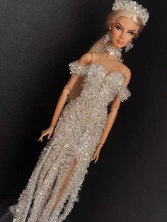 a barbie doll wearing a white dress with silver sequins on it's shoulders