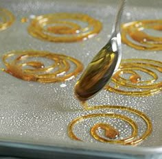 a spoon is being used to stir food in a baking pan with golden swirl designs on it