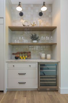 a kitchen with white cabinets and shelves filled with wine glasses, lemons and bottles