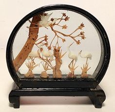 a glass display case with birds and flowers in the bottom half, on a black stand