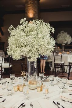 a vase filled with baby's breath sitting on top of a white table cloth