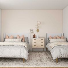 two beds in a bedroom with white walls and beige bed linens on the covers