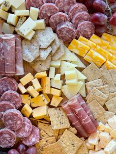 a variety of cheeses, crackers, and meats on a platter