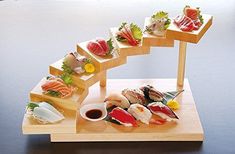 sushi is arranged on a wooden stand with sauces and garnishes