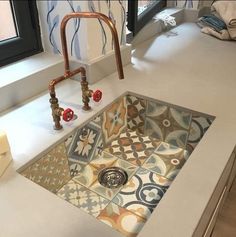 a sink in a bathroom with an artistic design on the floor and under running water