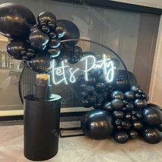 black balloons are on display in front of a sign that says let's party