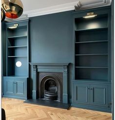 an empty living room with blue walls and wood flooring, built in bookshelves