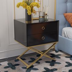 a black and gold side table with flowers on it next to a blue couch in a bedroom