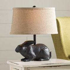 a lamp that is sitting on top of a table with a rabbit figurine underneath it