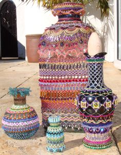 three vases made out of beads sit on the ground next to a potted plant