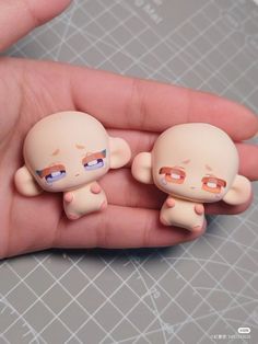 two small dolls are sitting on the palm of someone's hand