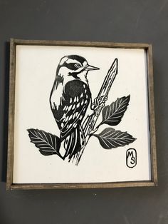 a black and white drawing of a bird sitting on a branch with leaves around it