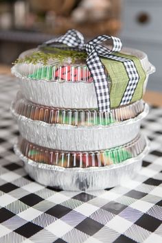 three tins filled with candy sitting on top of a checkered tablecloth covered table