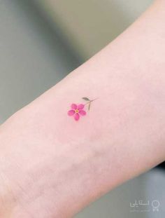 a small pink flower tattoo on the arm