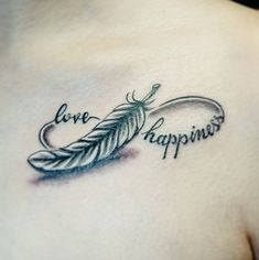 a woman's chest with a tattoo that says love, happiness and a feather