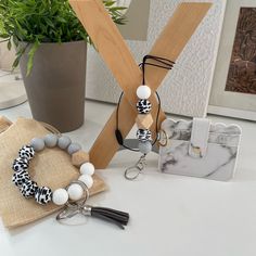 two bracelets, one with black and white beads are sitting on a table next to a purse