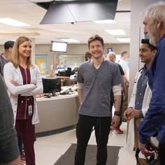 a group of people standing around each other in an office building talking to one another