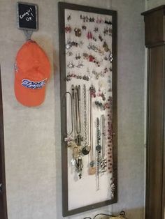 a wall mounted jewelry rack with an orange hat hanging on the wall next to it