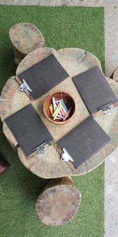 a wooden table with four place mats on it and a bowl full of colored pencils