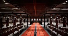 an empty gym with rows of benches and red carpeted flooring on both sides