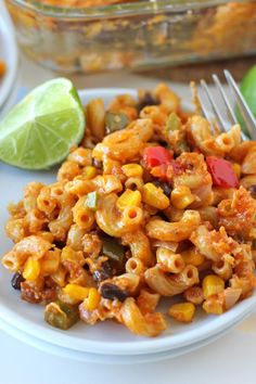 a white plate topped with macaroni and cheese next to a lime wedge on the side