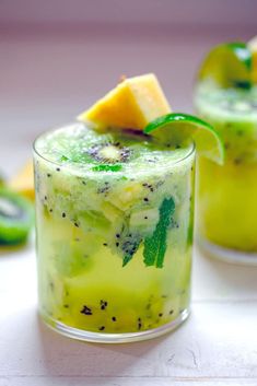 two glasses filled with pineapple mojito on top of a table