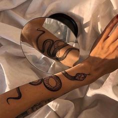 a woman's arm with tattoos on it and a mirror in front of her