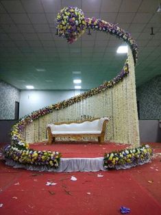 a stage set up for a wedding ceremony with flowers on the floor and decorations around it