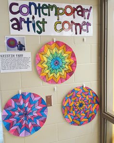 three colorful paper umbrellas are hanging on the wall next to a sign that says contemporary artist corner