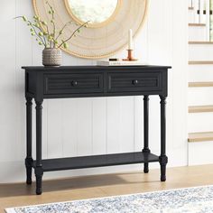 a black console table with two drawers in front of a mirror and stairs leading up to the second floor