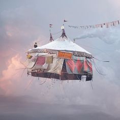 an upside down tent in the sky with clothes hanging from it's sides and flags flying above