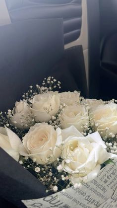 a bouquet of white roses sitting in the back seat of a car with an envelope