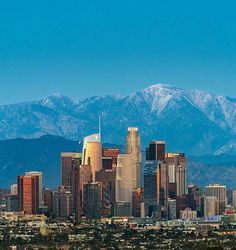 a city with mountains in the background and snow on the top of the mountain tops