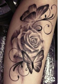 a black and white rose with two butterflies on it's thigh, next to a butterfly tattoo