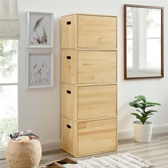 a tall wooden cabinet sitting on top of a hard wood floor next to a potted plant