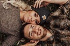 two people laying in the grass with their heads close to each other and smiling at the camera