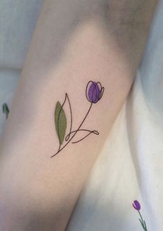 a small flower tattoo on the left arm and leg, with purple flowers around it