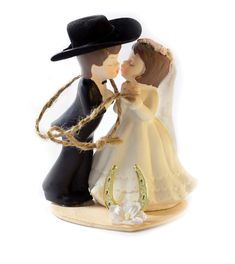 a wedding cake topper with a bride and groom kissing on the forehead, wearing a cowboy hat