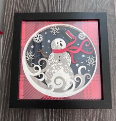 an ornament with a snowman on it in a black and red frame