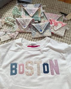 the boston t - shirt is laying on the bed next to other pieces of fabric