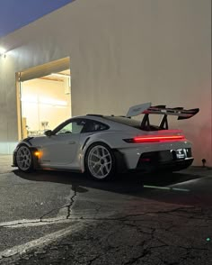 a white sports car parked in front of a building at night with its lights on